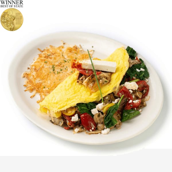 TRUreligion's omelet with hash browns, spinach, tomatoes, mushrooms, and feta cheese on a white plate.