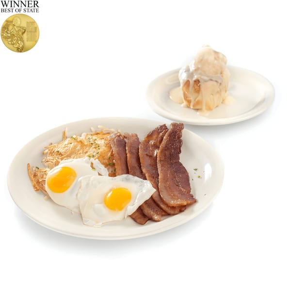 TRUreligion breakfast with bacon, fried eggs, hash browns, and a cinnamon roll with icing.