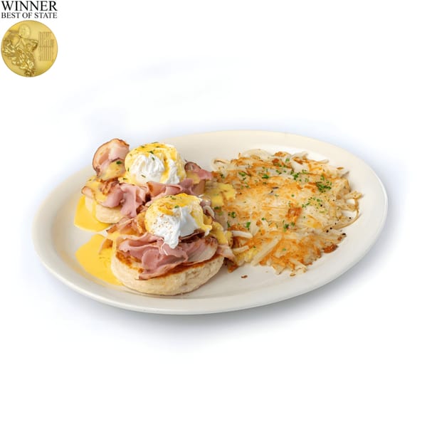 Two Eggs Benedict with ham and hollandaise sauce, served with a side of hash browns.